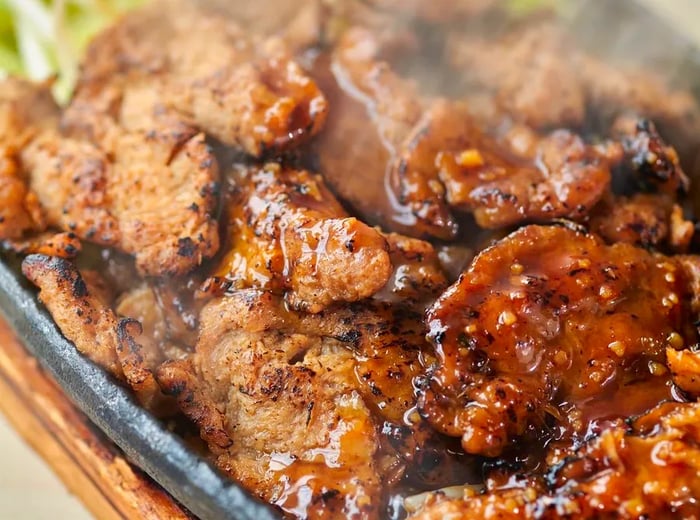 A cast-iron plate sizzling with non-meat served alongside shredded cabbage.