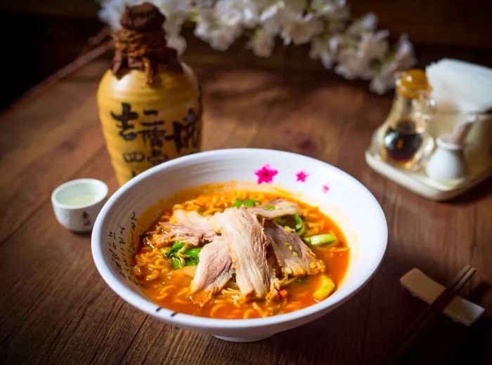 A steaming bowl of ramen topped with slices of meat.