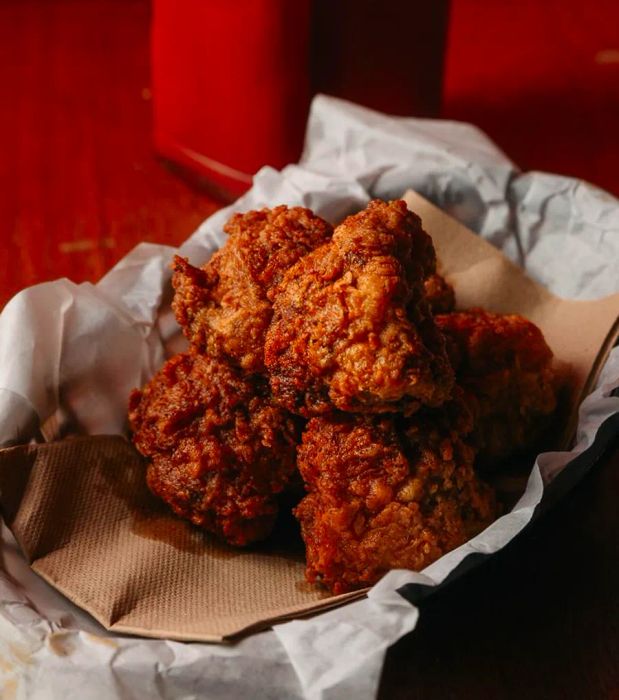 Chunks of crispy, deep-fried cauliflower served in a basket lined with paper.