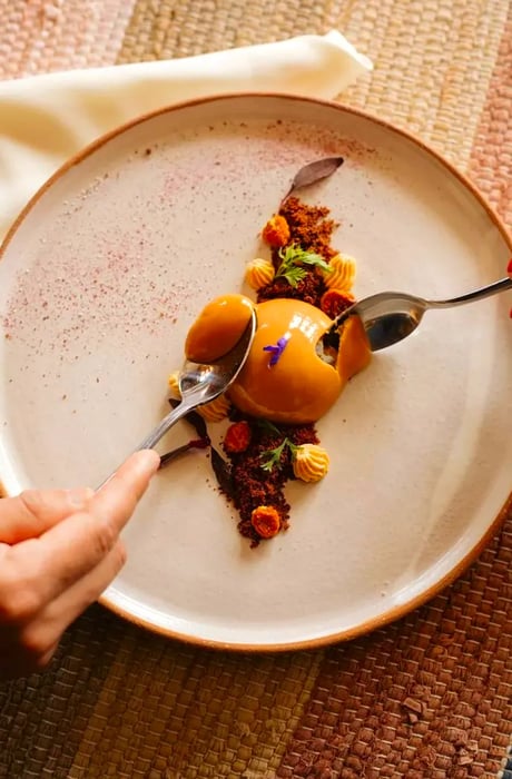 Two diners enjoy an elaborate dessert, each armed with a spoon.