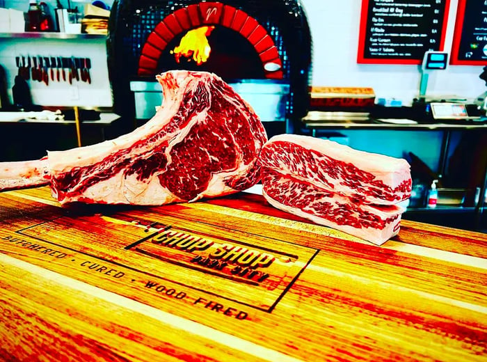 Two large cuts of raw steak displayed on a cutting board.