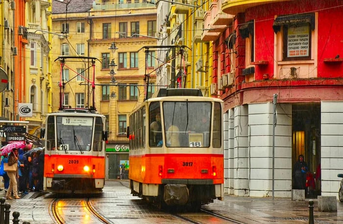 A view featuring two orange tram cars in central Sofia, Bulgaria