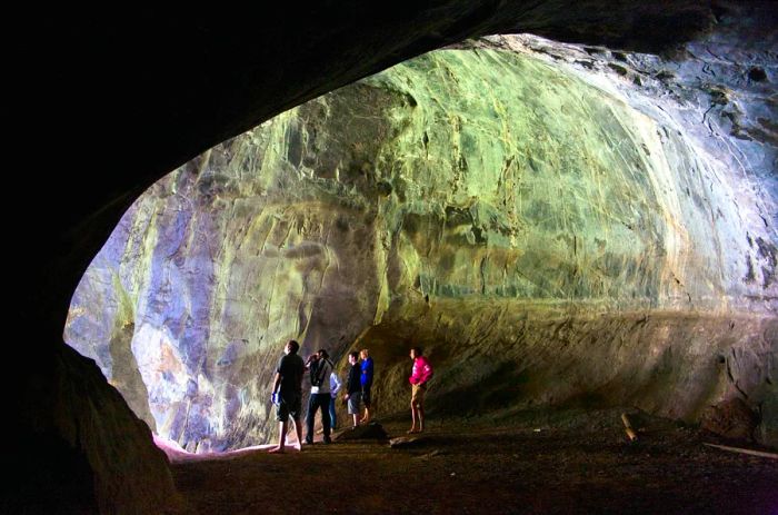 A group of individuals basking in the sunlight at the entrance of Patok Cave near Nong Khiaw, Laos