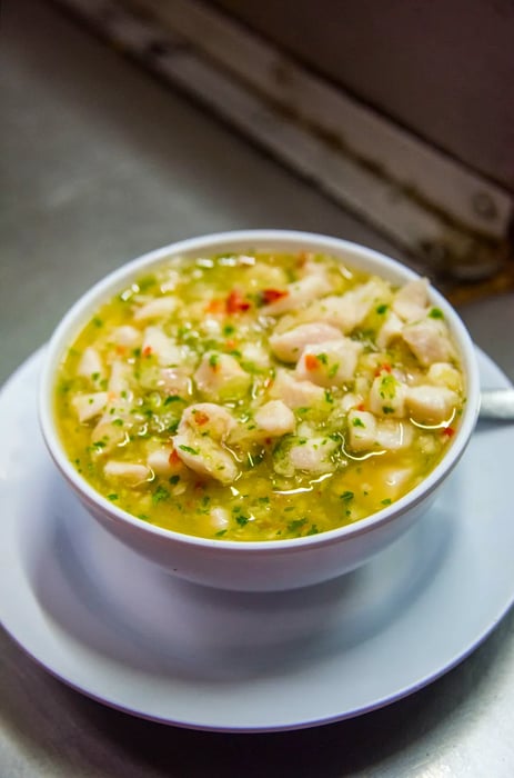 A bowl of fresh seafood ceviche rests on a metal counter.