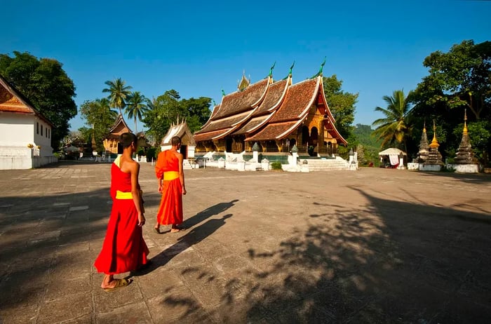 Two novice monks strolling through the grounds of Wat Xieng Thong temple in Luang Prabang, Laos