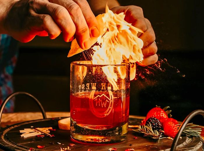 A bartender ignites a cocktail, creating a ball of flame.