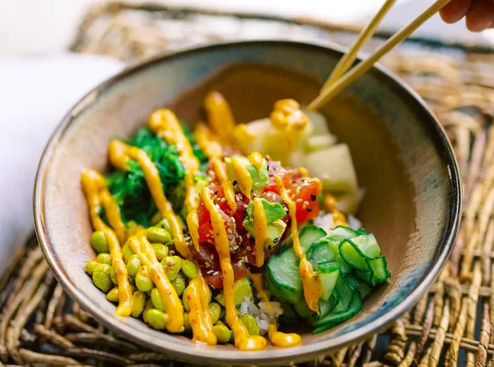 Chopsticks poised above a poke bowl.