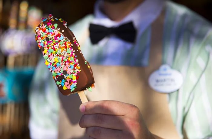 A hand-dipped ice cream bar at Clarabelle’s in Disney’s California Adventure, presented by a staff member.