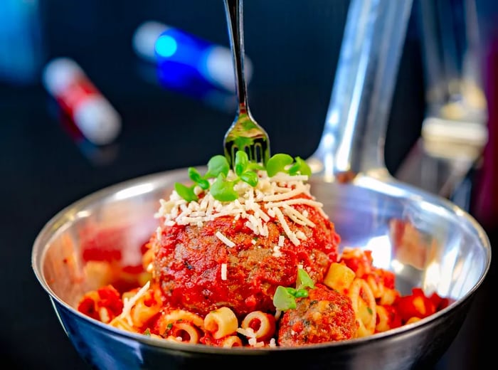 A silver bowl filled with pasta and a meatball at Disneyland.