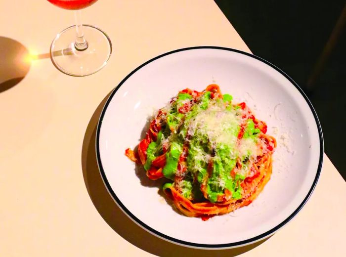 A dish of pasta adorned with various sauces, accompanied by a glass of rosé wine