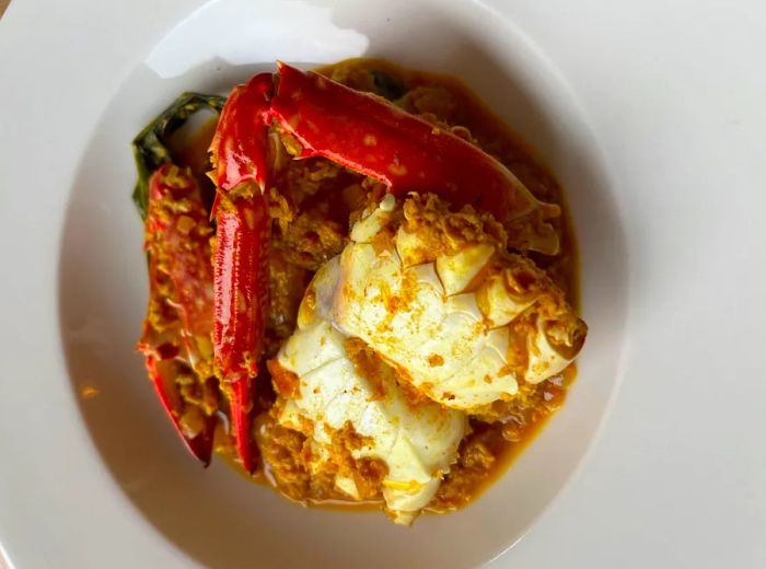 A sizable piece of crab meat attached to the legs, presented in a bowl with a delicate sauce.