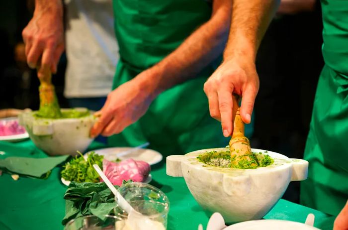 Chefs in a kitchen crafting Pesto basil sauce