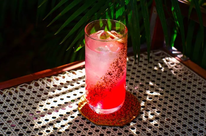 A tall red cocktail adorned with a spice mixture elegantly striped around the outside of the glass.