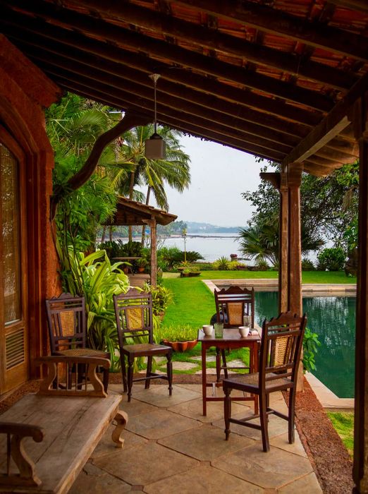 A cozy coffee table accompanied by a few chairs, situated on a porch overlooking a pool with a stunning bay view.