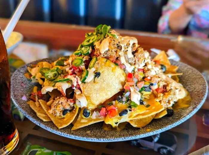 A vibrant plate of nachos loaded with lobster, beans, jalapeños, and melted cheese.