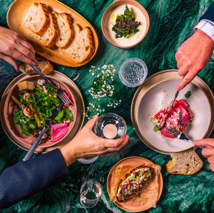 Diners enjoying a variety of dishes on a green marble table.