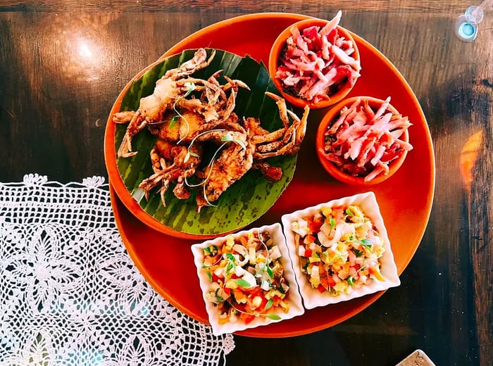 A platter of crispy fried crabs accompanied by small bowls of slaw and chopped salad on the side.