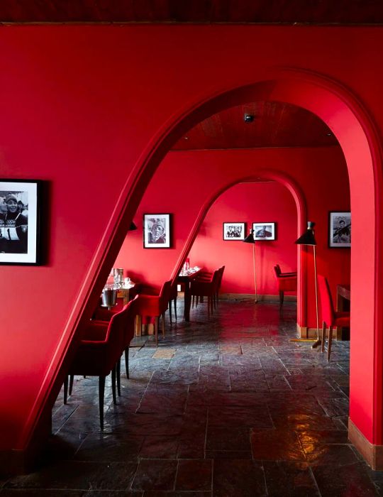 A series of quirky red archways framing dining spaces nestled in charming alcoves.