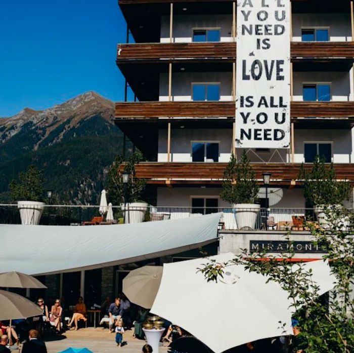 Guests relax on a hotel deck adorned with a banner proclaiming, “All you need is Love is all you need.”