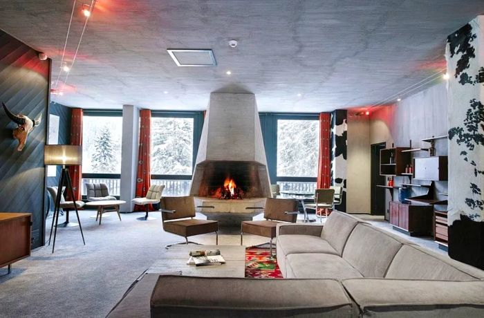 A lounge featuring midcentury decor and a spacious cement fireplace.