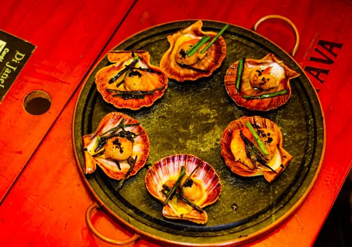 A plate of scallops garnished with sauce and sautéed vegetables