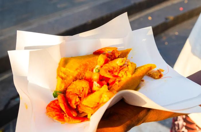 A customer holds an acarajé, opened to reveal the shrimp and other fillings within.