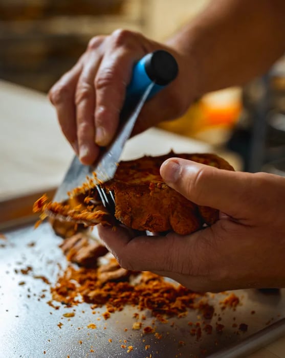 A baker skillfully uses a bench scraper to trim pastry dough.