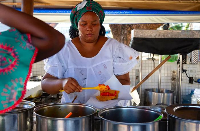 A chef fills an acarajé at a street stall.