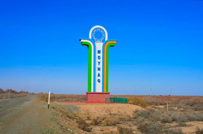 A striking roadside landmark greets travelers arriving in Moynaq (Muynak), featuring the vibrant colors of the Uzbek flag in Karakalpakstan, western Uzbekistan.