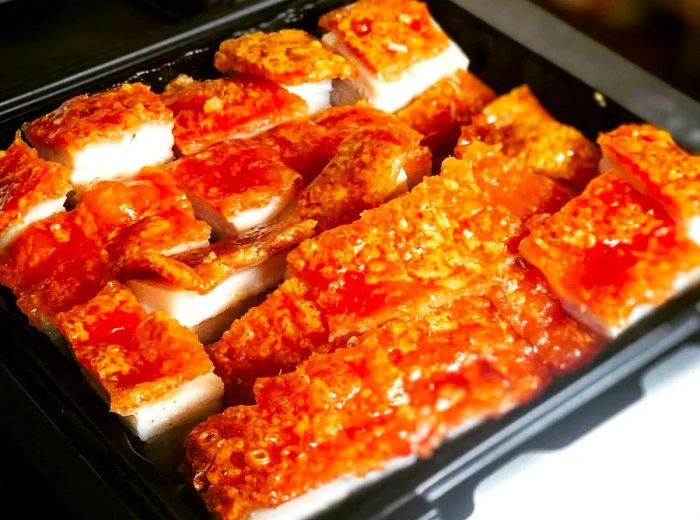 A takeout box filled with tender chopped roast pork topped with crispy skin.