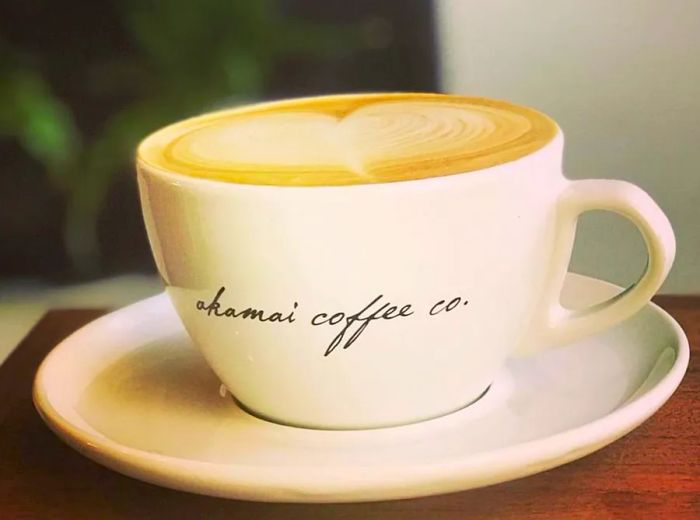 A latte overflowing in a coffee mug adorned with the café's name in elegant cursive.