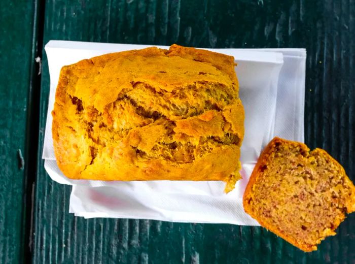 A freshly baked loaf of banana bread with a slice removed.