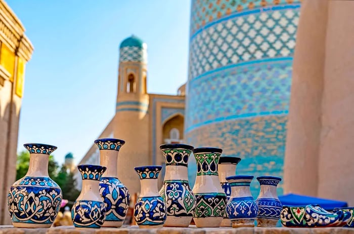 A display of small ceramic pots adorned with intricate blue-and-white glazed designs in front of a grand tiled structure