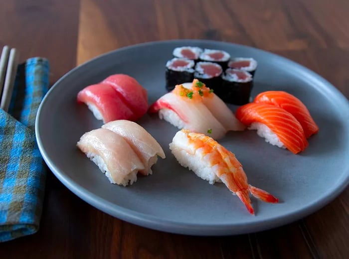 A platter featuring pairs of fish and shrimp nigiri alongside a maki roll.