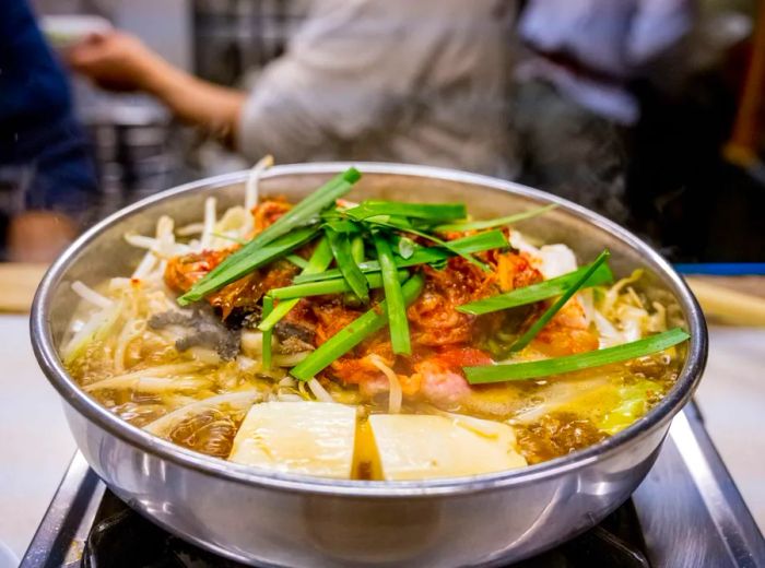 A steaming bowl of motsunabe filled with assorted meats and vegetables.