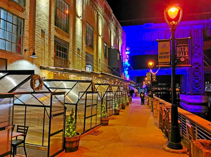 A line of cozy greenhouses with dining areas nestled along the riverfront