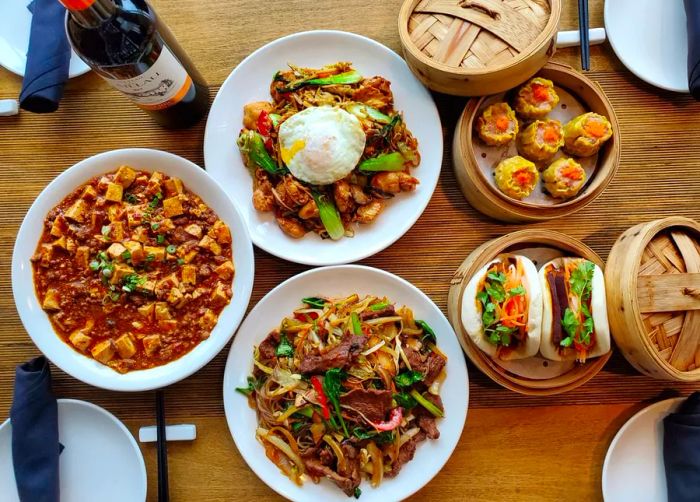 A table showcasing a variety of dishes including mapo tofu, bao, noodles, and dumplings.