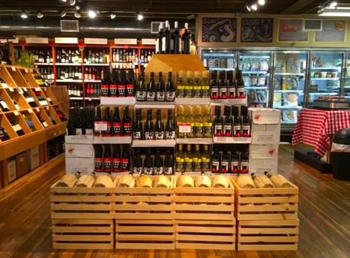 A standalone display showcasing wine bottles arranged in wooden boxes, accompanied by shelves filled with upright bottles of red and white varieties.