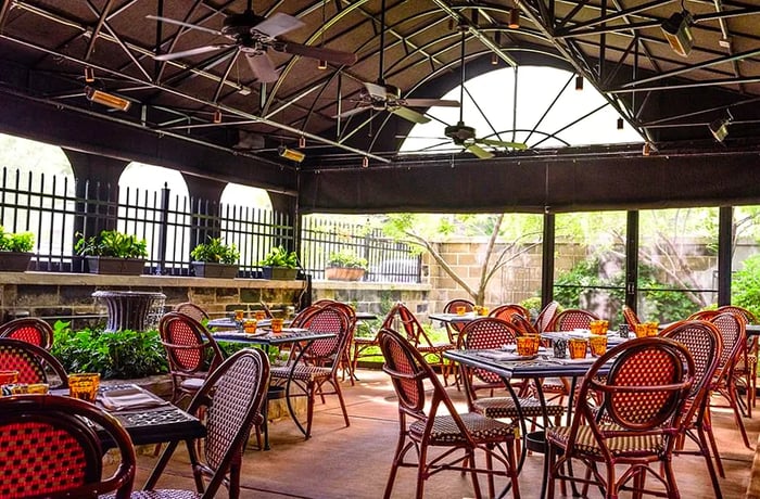 An airy, hanger-like outdoor space adorned with tables and cane patio chairs.