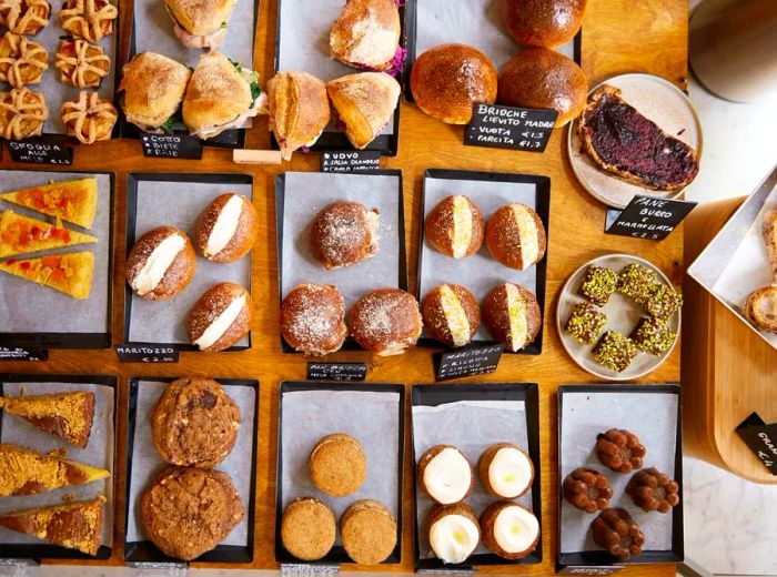 Pastries displayed on individual trays with small chalkboard labels