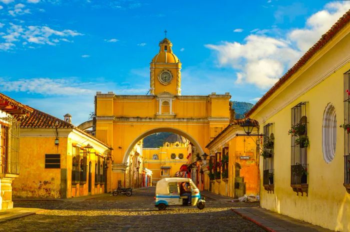 A tuk-tuk taxi drives past the Arch of Santa Catalina in Antigua, Guatemala.