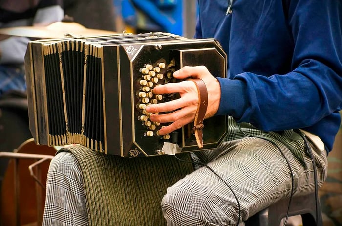 A close-up shot of a person playing an accordion on their knee in Buenos Aires.