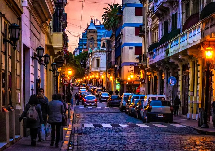 As dusk falls, people stroll along a sidewalk bordering the cobblestone streets in Buenos Aires' San Telmo neighborhood.