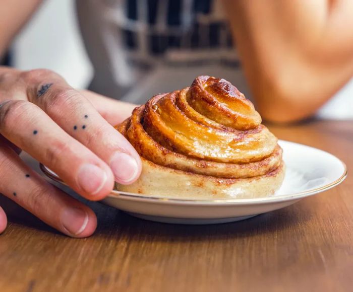 A close-up of a hand resting on a beautifully swirled pastry.