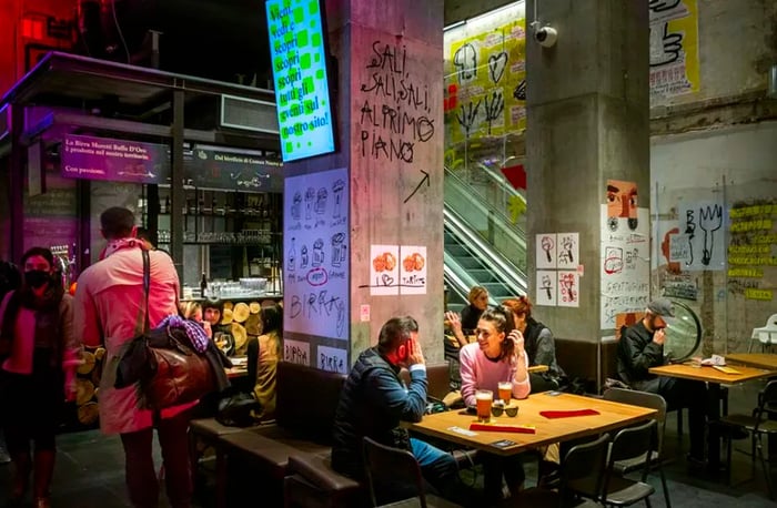 Diners enjoy their meals amid concrete pillars adorned with graffiti related to the restaurant concepts.