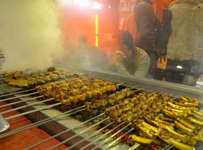 Grilled meat skewers over a smoky flame.