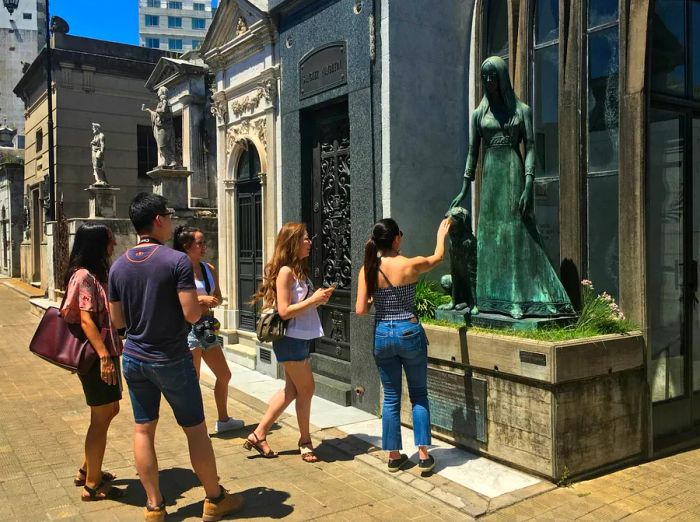 A group of young tourists admiring a stunning statue at a mausoleum in Recoleta Cemetery, Buenos Aires.