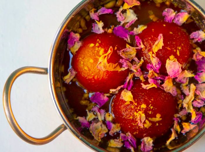 Three gulab jamun garnished with edible flowers.