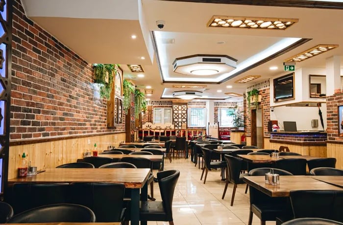 A red brick dining area adorned with skylights, intricate woodwork, and cascading plants.