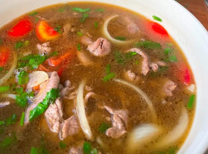 A bowl of pho adorned with slices of meat and fresh vegetables.